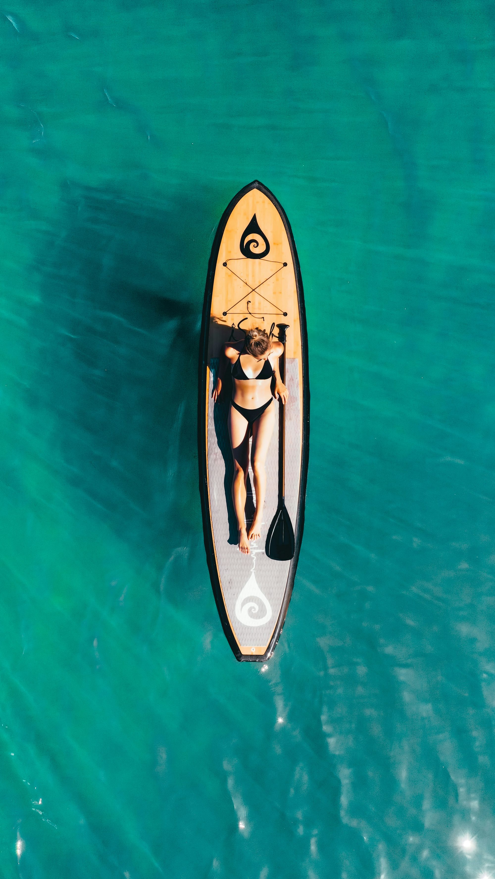 Aerial view of a paddleboarder resting on clear turquoise water