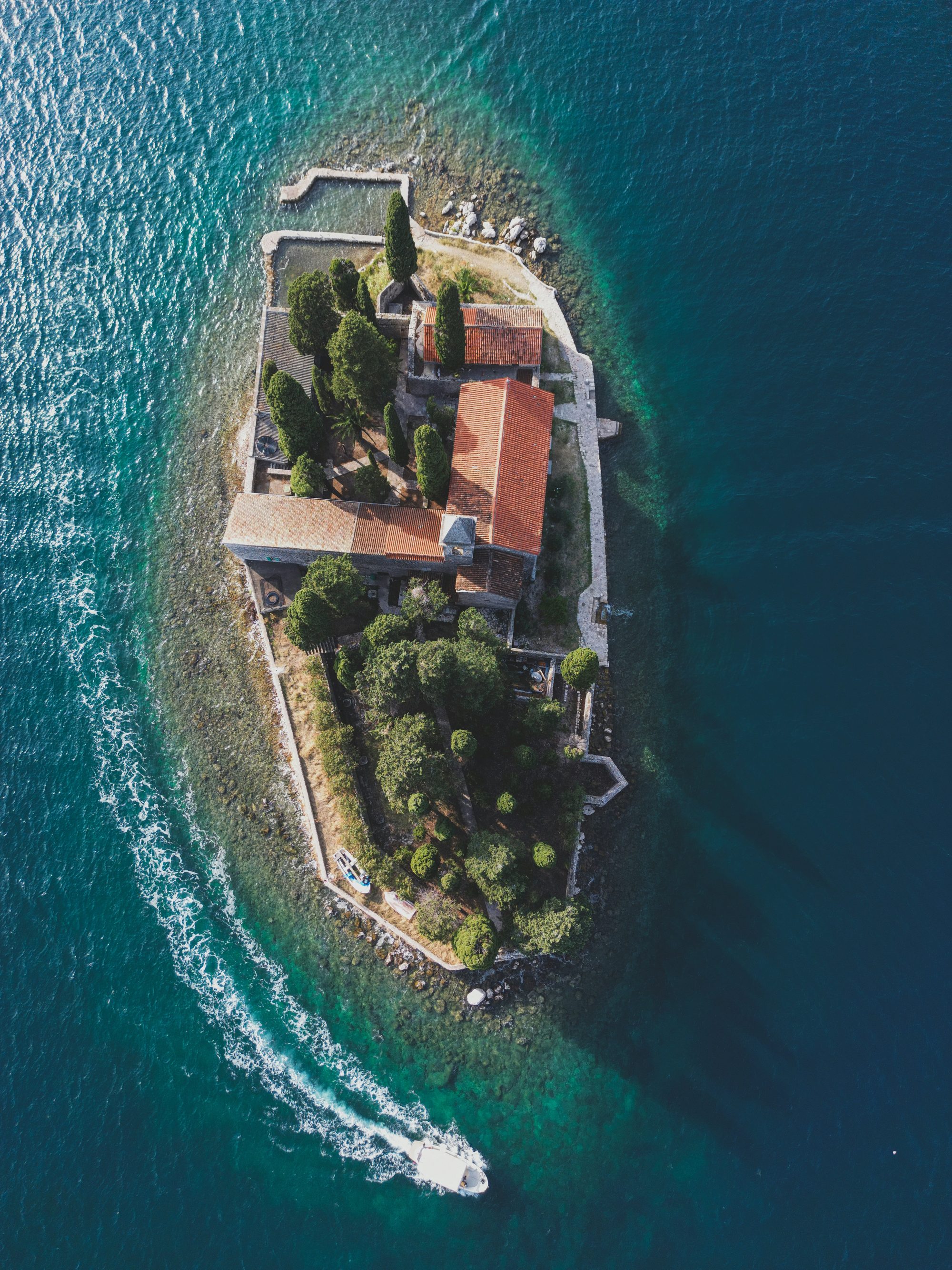 Aerial view of a small island with a stone monastery in the bay