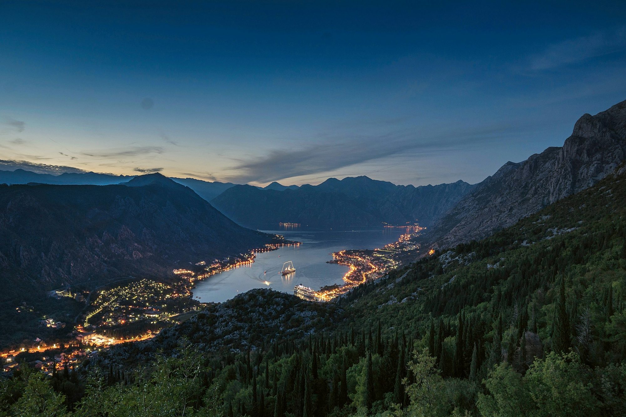Bay of Kotor at dusk with town lights reflecting on the water